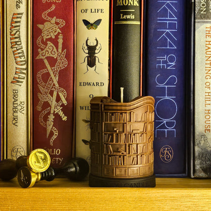 Decorative candle shaped like a bookshelf with books in the background