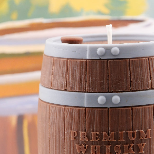Candle in the shape of a wooden barrel with 'PREMIUM WHISKY' text, blurred background