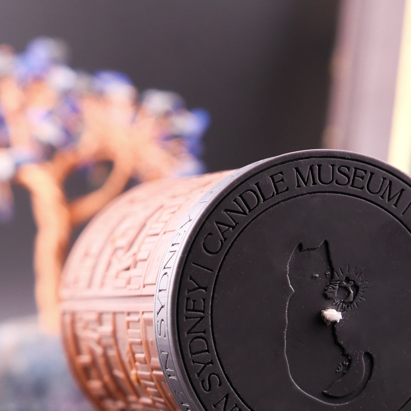 Candle with 'Sydney Candle Museum' branding and a cat silhouette on a blurred background