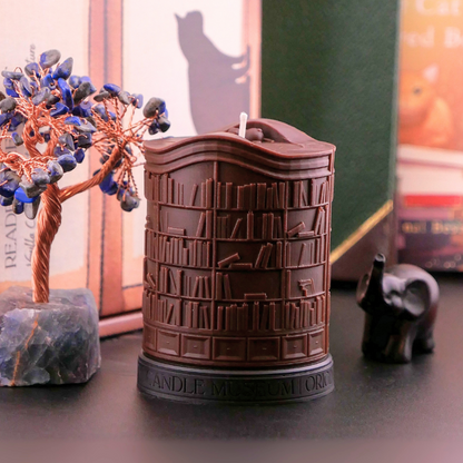 Brown-colored candle with book design on a surface with decorative items.