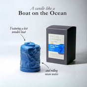 Blue candle shaped like a boat on the ocean with packaging labeled 'Ocean Odyssey' on a light gray background.