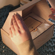 A bookshelf candle being unboxed from an art crate style gift box.