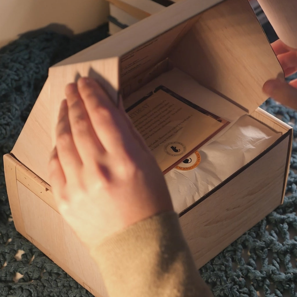 A bookshelf candle being unboxed from an art crate style gift box.